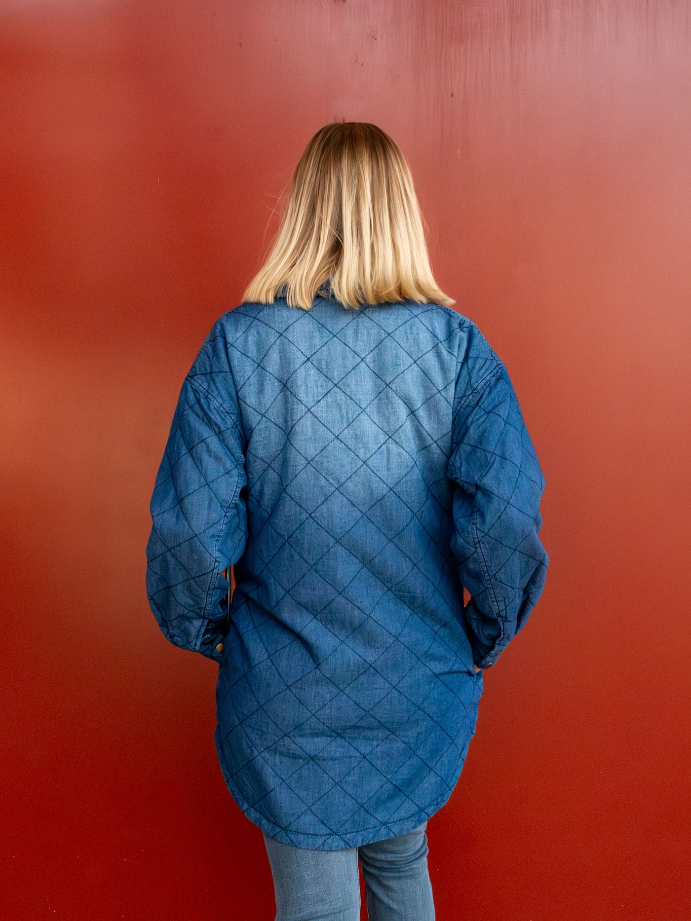 A model wearing a blue quilted shacket that buttons down the front. The model paired it with light wash jeans.