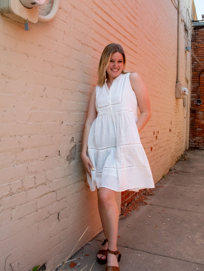 A model wearing a white empire waist eyelet dress and brown platform sandals.