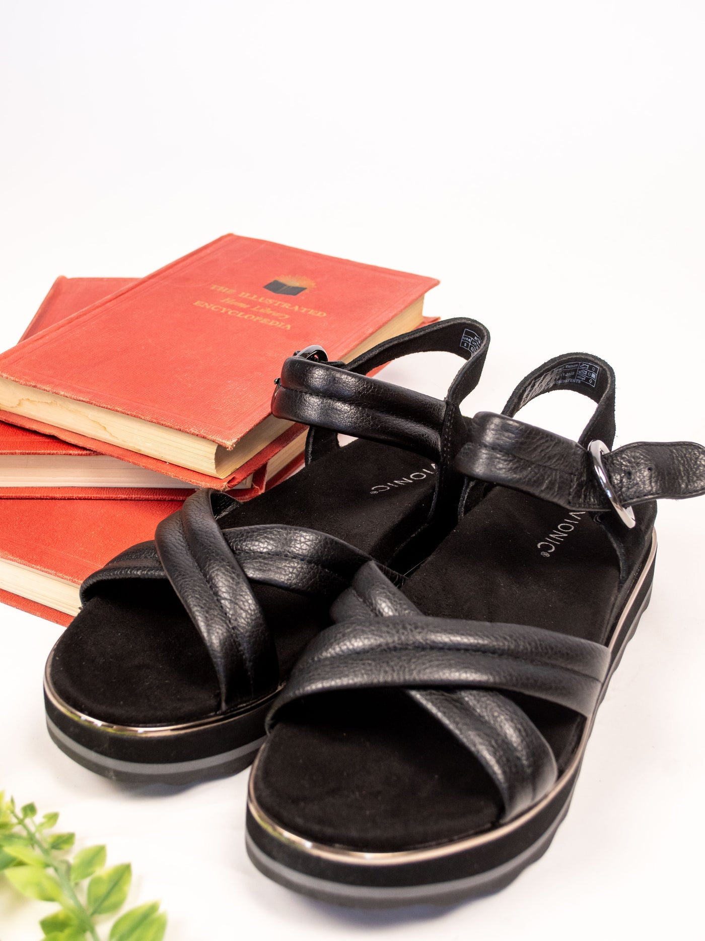 A pair of black flatworm sandal with cross foot straps on the front and adjustable back straps.