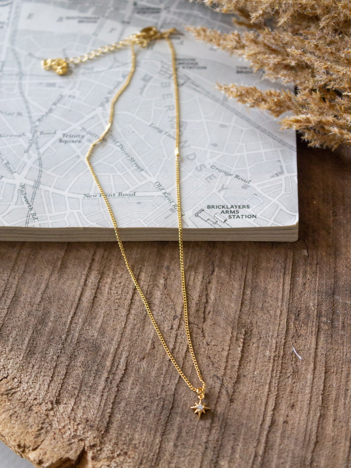 A gold chain necklace with a small star charm with a cubic crystal.