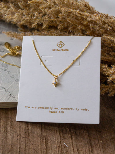 A gold chain necklace with a small star charm with a cubic crystal.