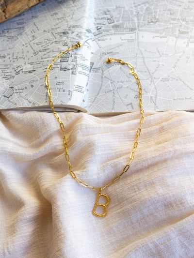 A square link/ paperclip style chain necklace with a twisted capital B attached to it.