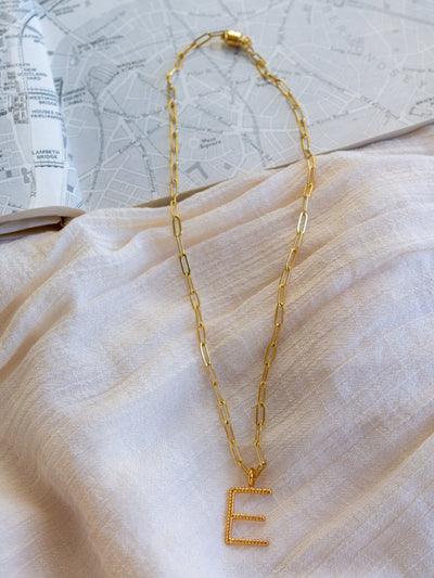 A square link/ paperclip style chain necklace with a twisted capital E attached to it.