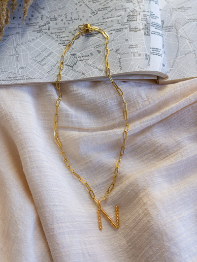 A square link/ paperclip style chain necklace with a twisted capital N attached to it.