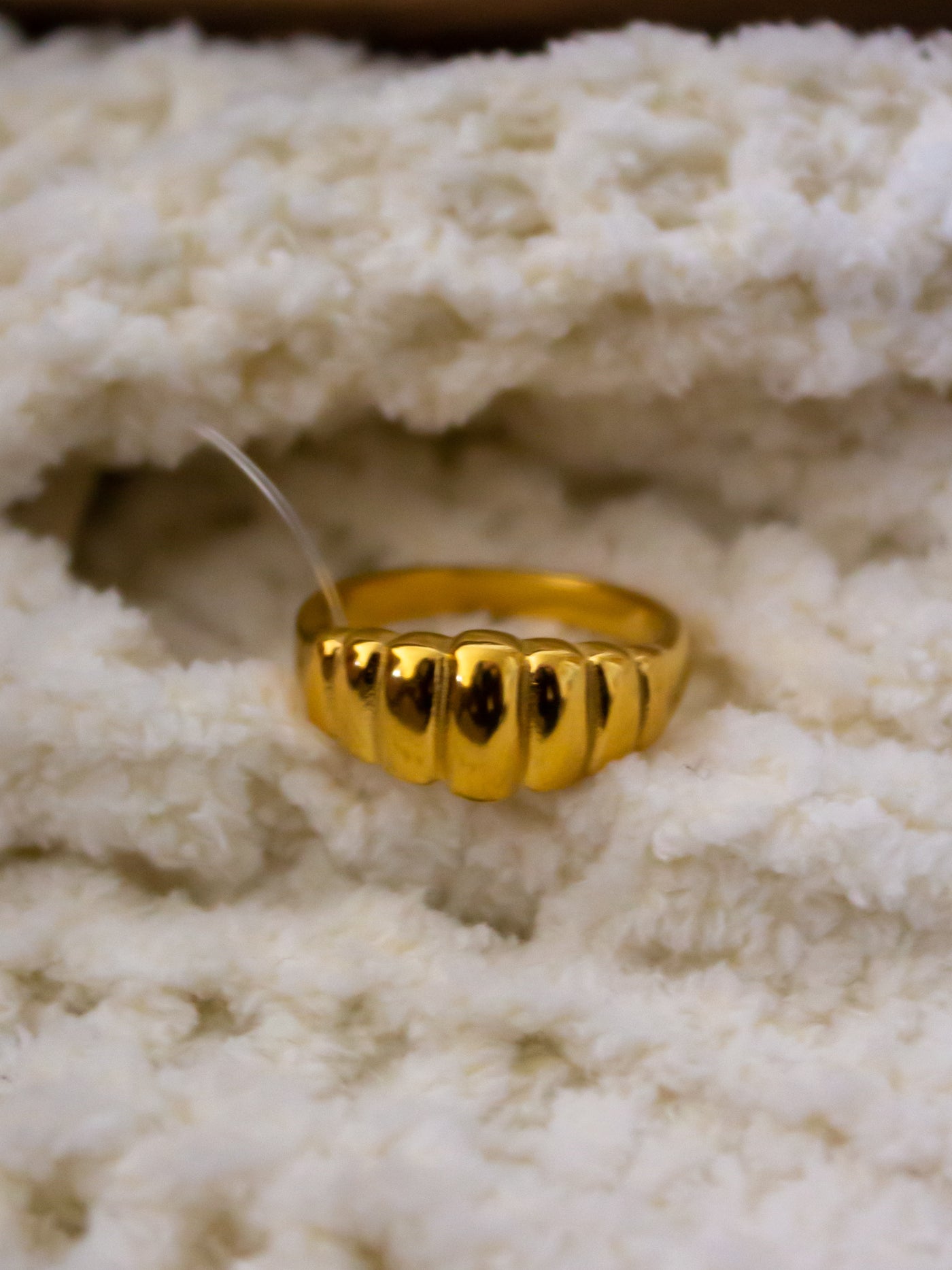 A crown ring with rigid design on it that is gold.