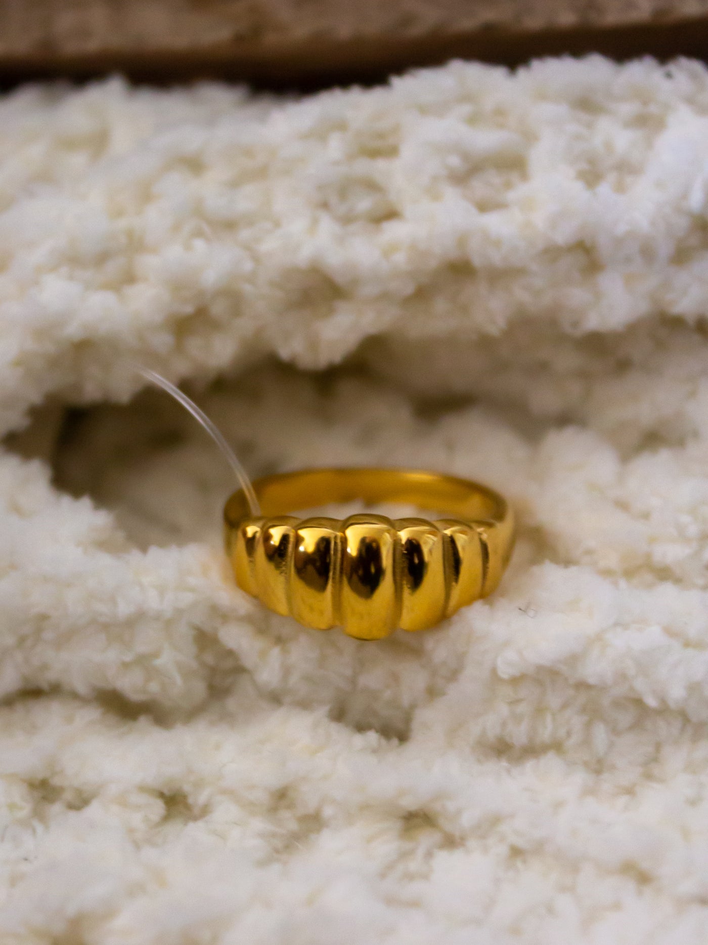 A crown ring with rigid design on it that is gold.