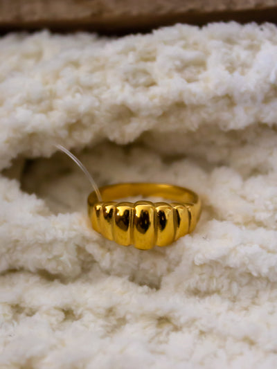 A crown ring with rigid design on it that is gold.