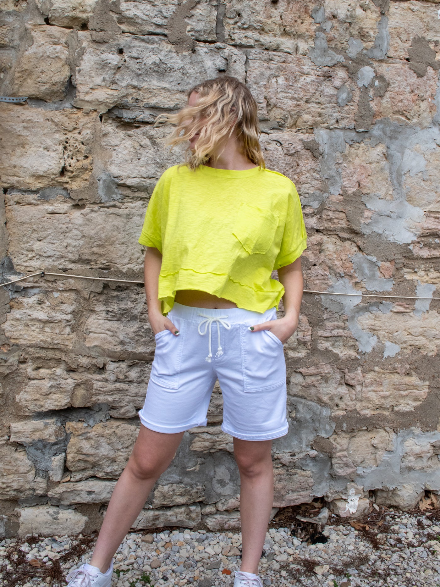 A model wearing a lime colored boxy tee with white Bermuda sailor shorts with white sneakers.
