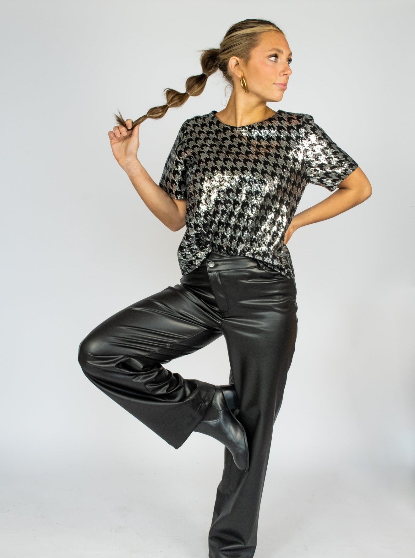 A model wearing a black and white houndstooth sequin tee with black pleather pants.
