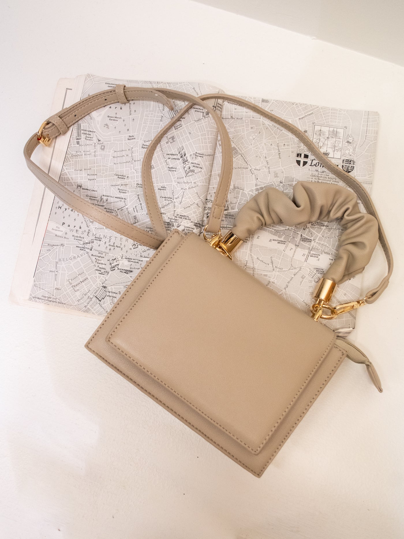A cream purse with a top handle and a removable/ adjustable crossbody strap that has a magnetic closure.