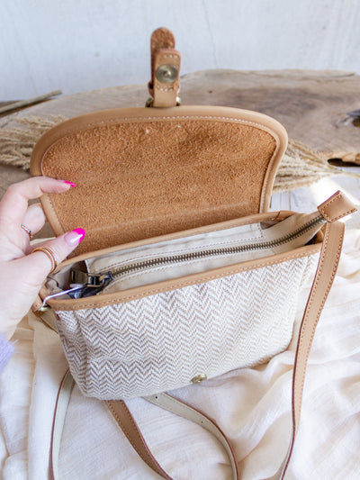 A herringbone pattern bag in cream and taupe. The bag has vegan leather accents with a pantina style flapper. 