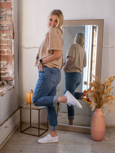 A model wearing a pair of cuffed boyfriend jeans with a graphic tee and white sneakers.