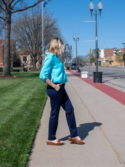 A model wearing navy knit trousers with a turquoise airflow blouse and brown platform sandals.