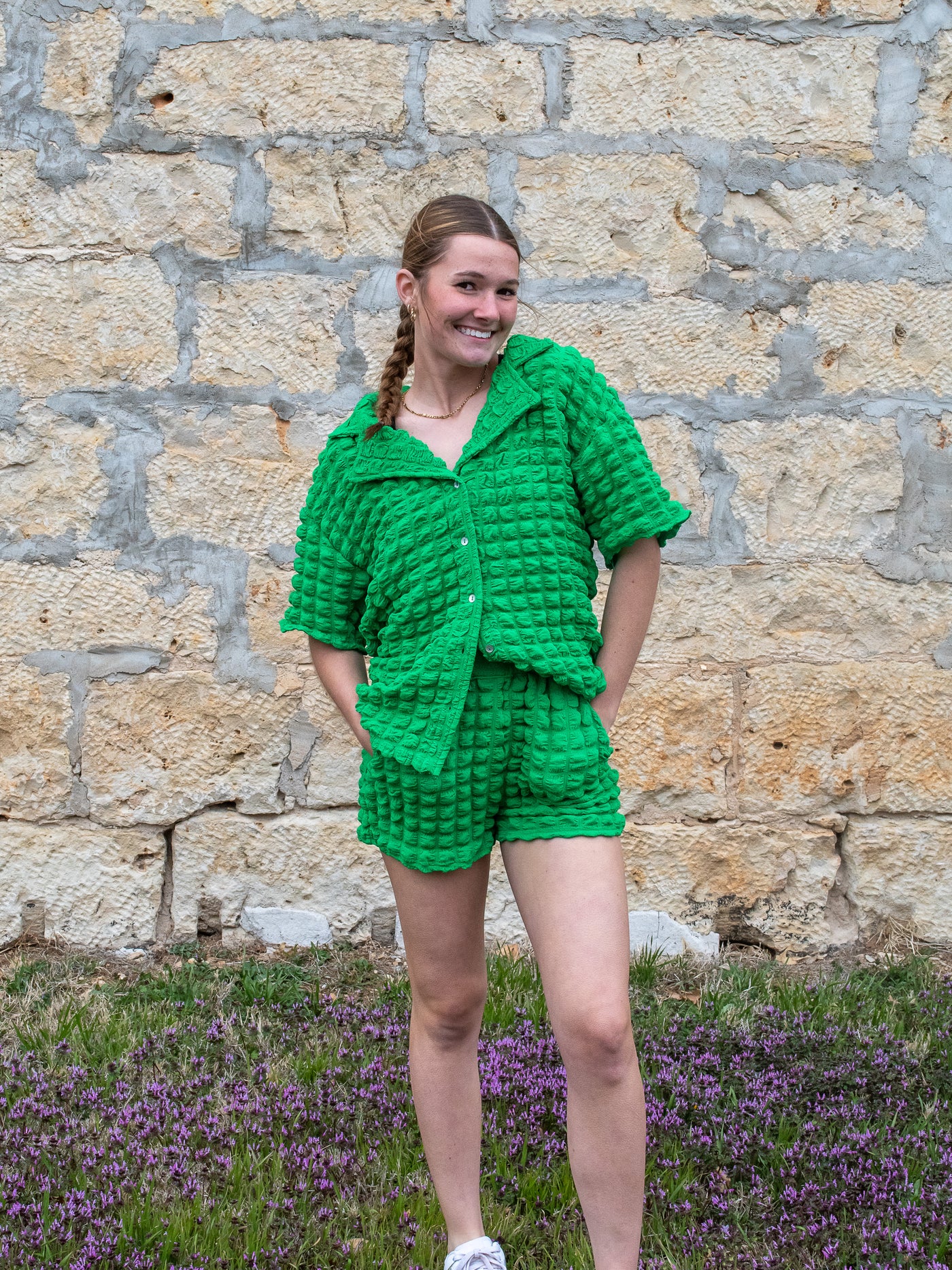A model wearing a green puffy short sleeve button down shirt will a collar lapel. She has it on with matching green shorts.