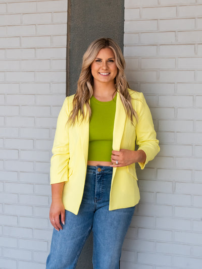 A model wearing a lime shirred sleeve blazer over a green tank with denim.