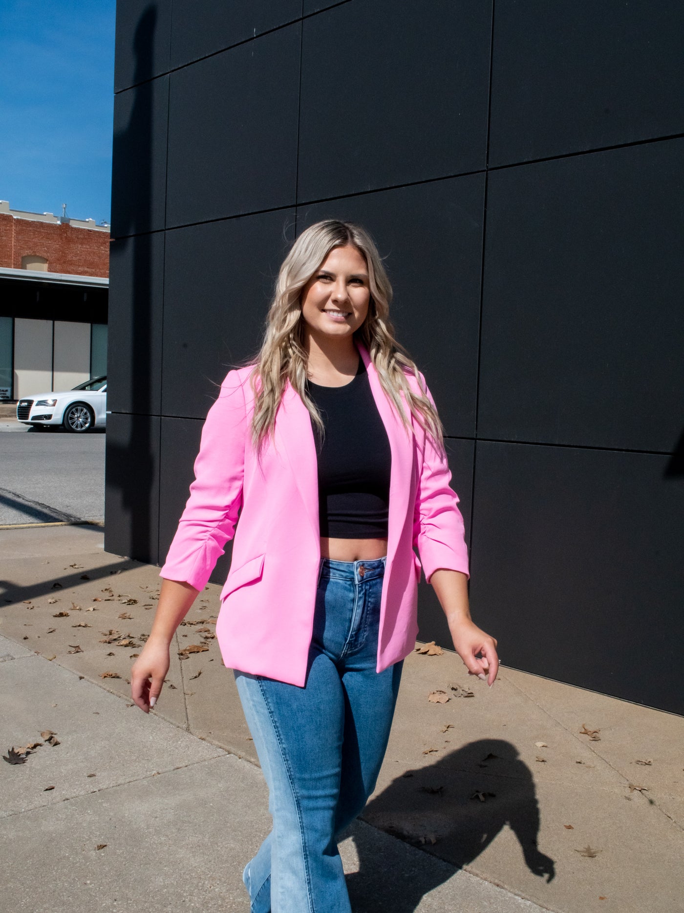 A model wearing a hot pink shirred sleeve blazer over a black tank with denim.