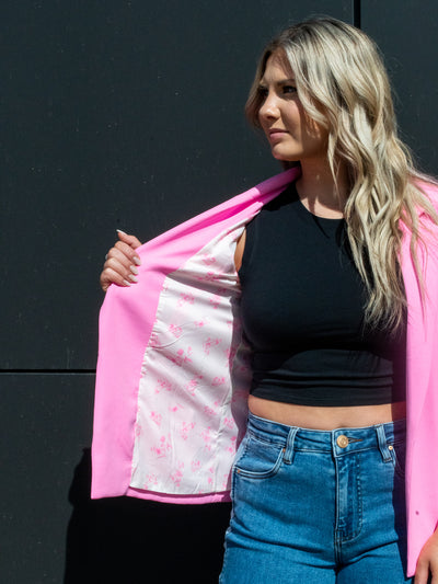 A model wearing a hot pink shirred sleeve blazer over a black tank with denim.