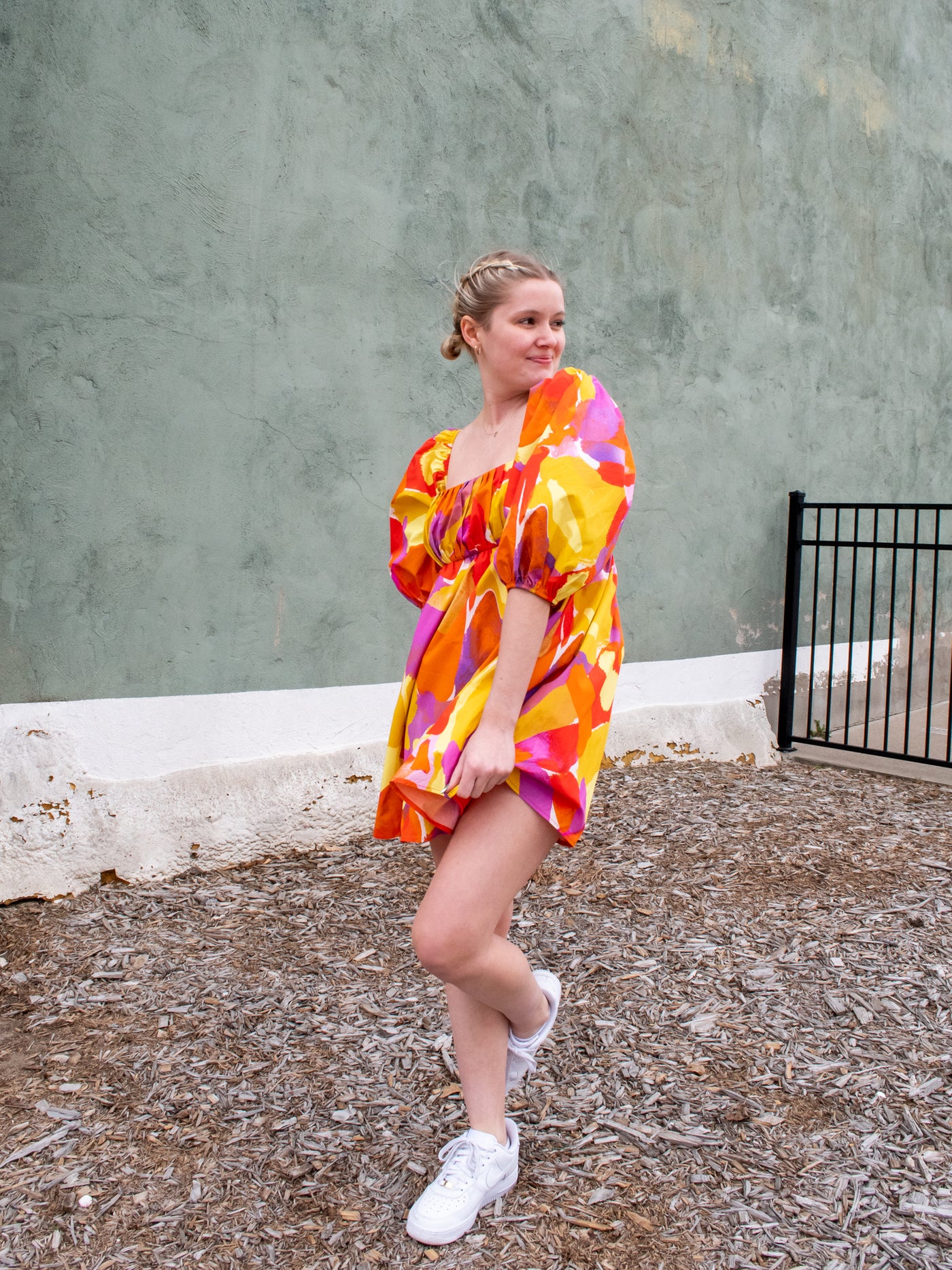 A pink, orange, purple, and yellow empire waist mini dress with puff sleeves.