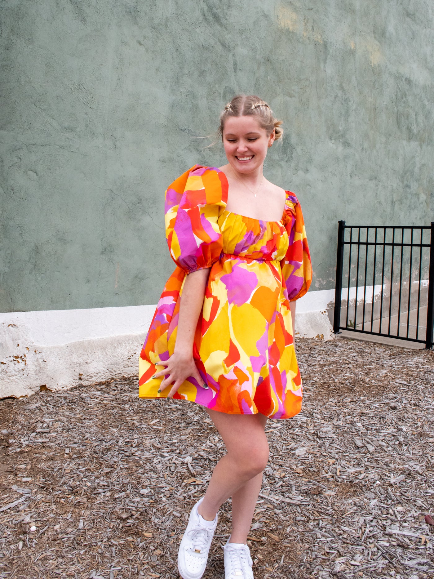 A pink, orange, purple, and yellow empire waist mini dress with puff sleeves.