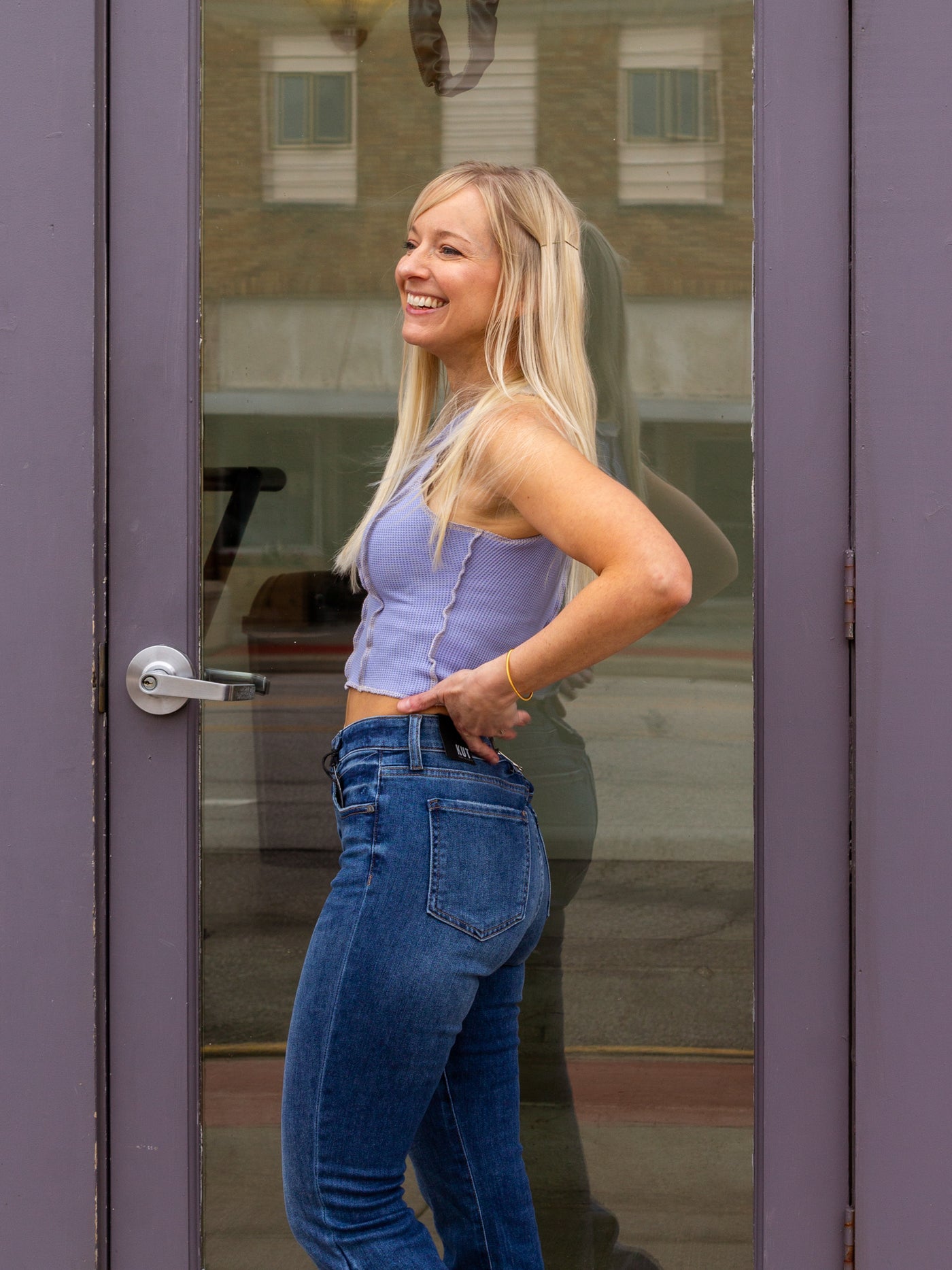 A model wearing a blue Waffle-Knit Round Neck Inverted Princess Crop Top with a pair of white sneakers and a pair of dark wash medium rise flare jeans.