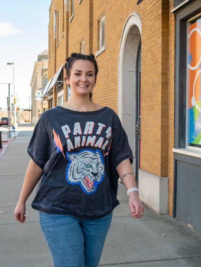 A model wearing a slouchy fit gray graphic sweatshirt. The sweatshirt has short sleeves and says "party animal" with a tiger graphic. She has it paired with jeans..
