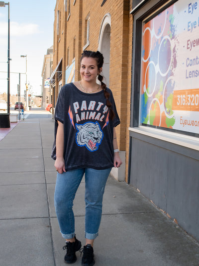A model wearing a slouchy fit gray graphic sweatshirt. The sweatshirt has short sleeves and says "party animal" with a tiger graphic. She has it paired with cropped jeans and black tennis shoes..