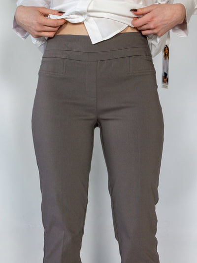 A model wearing a pair of dark grey colored cigarette pants and a white button down blouse.