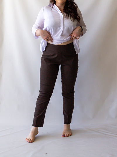 A model wearing a pair of heather brown colored cigarette pants and a white blouse.