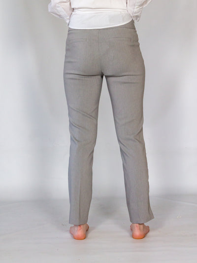 A model wearing a pair of grey colored cigarette pants and a white button down blouse.