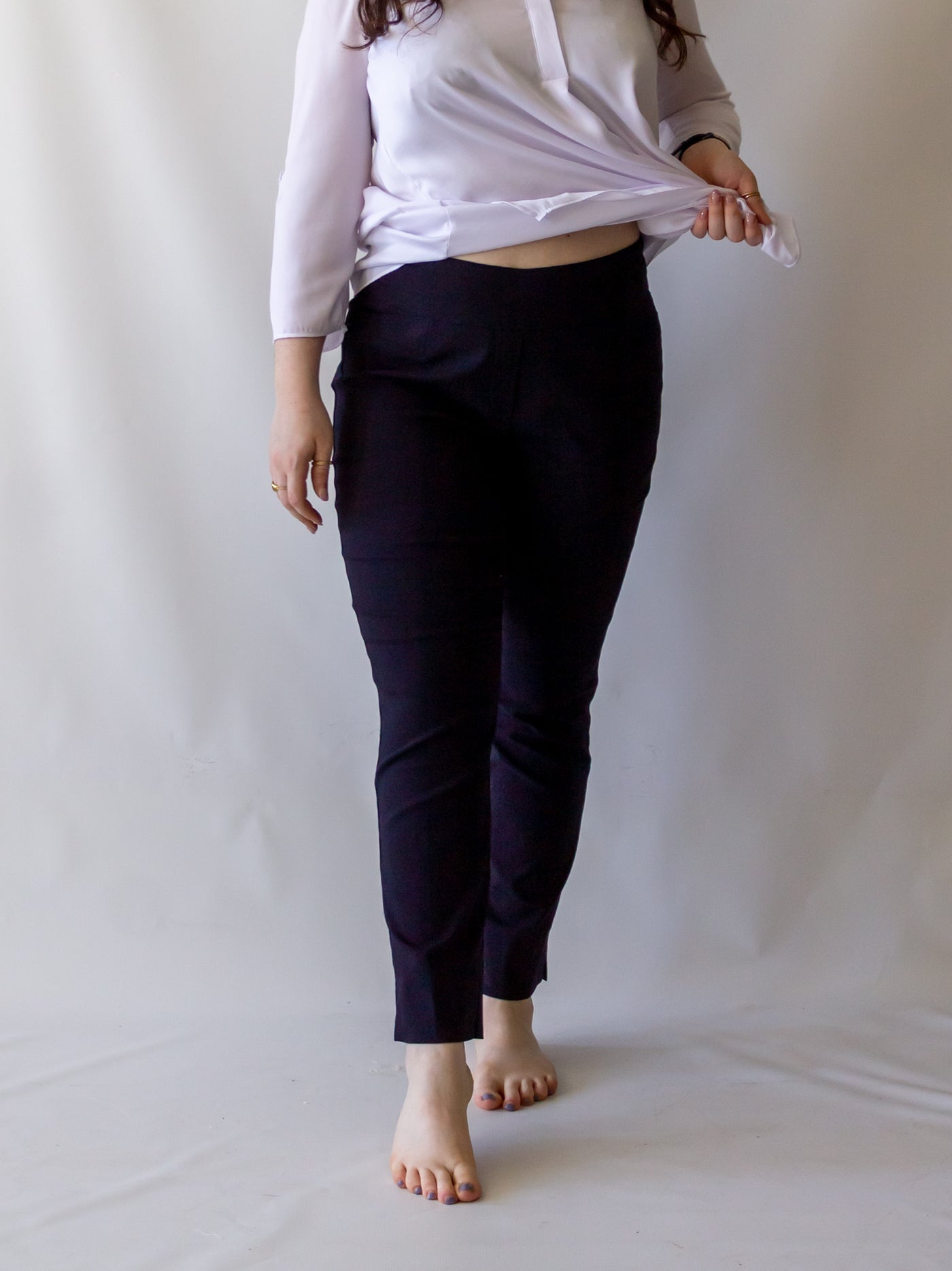 A model wearing a pair of navy colored cigarette pants and a white blouse.