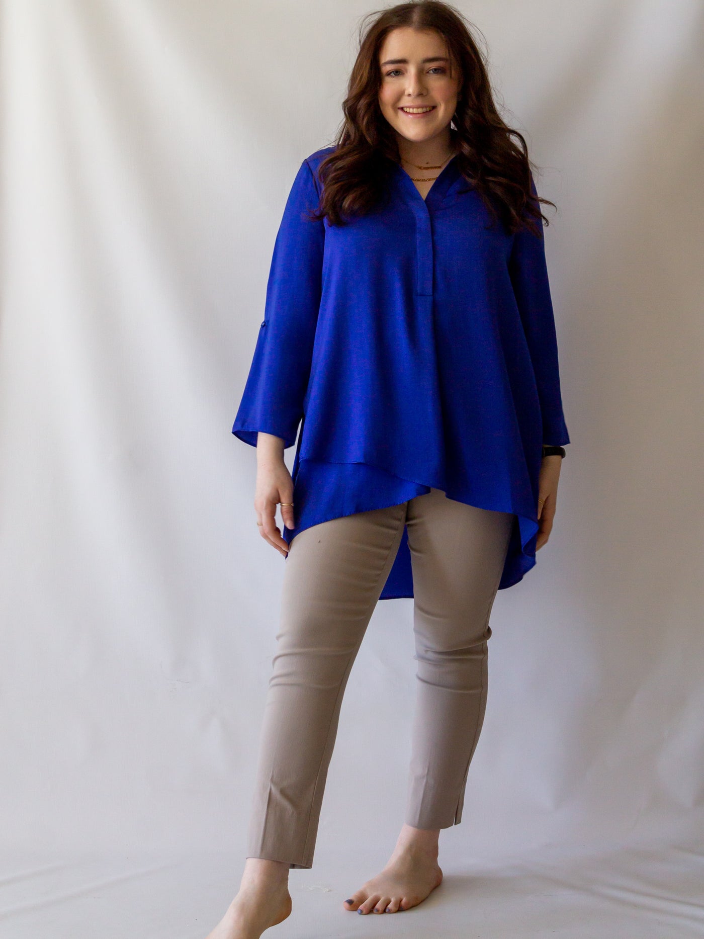 A model wearing a pair of sand colored cigarette pants and a royal blue blouse.