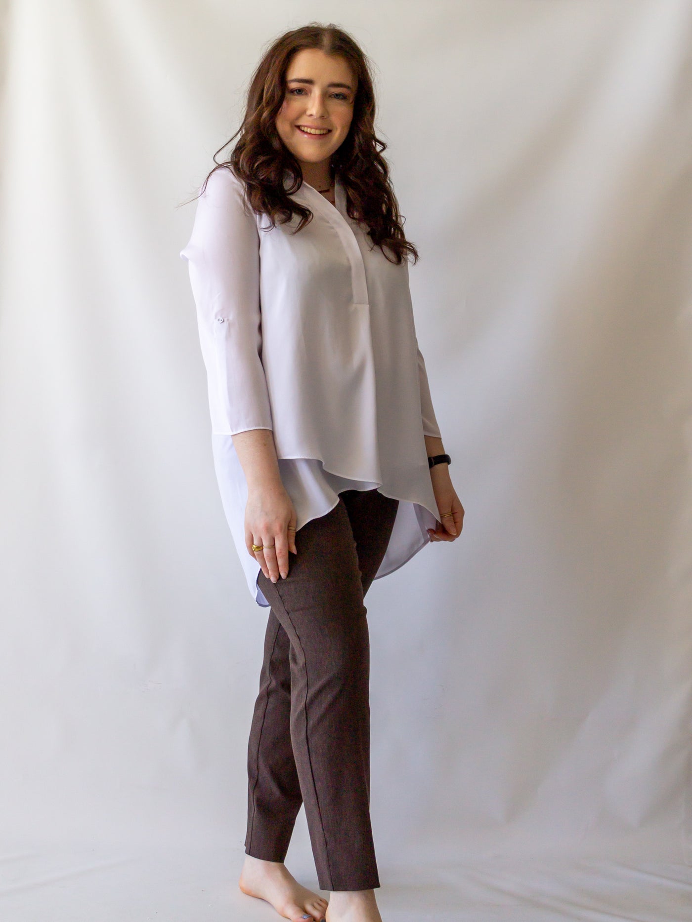 A model wearing a white, long flowy pants with heather brown colored cigarette style pants.