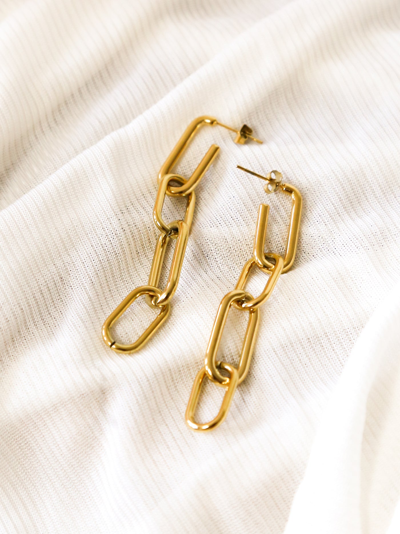 A pair of gold paperclip link earrings.
