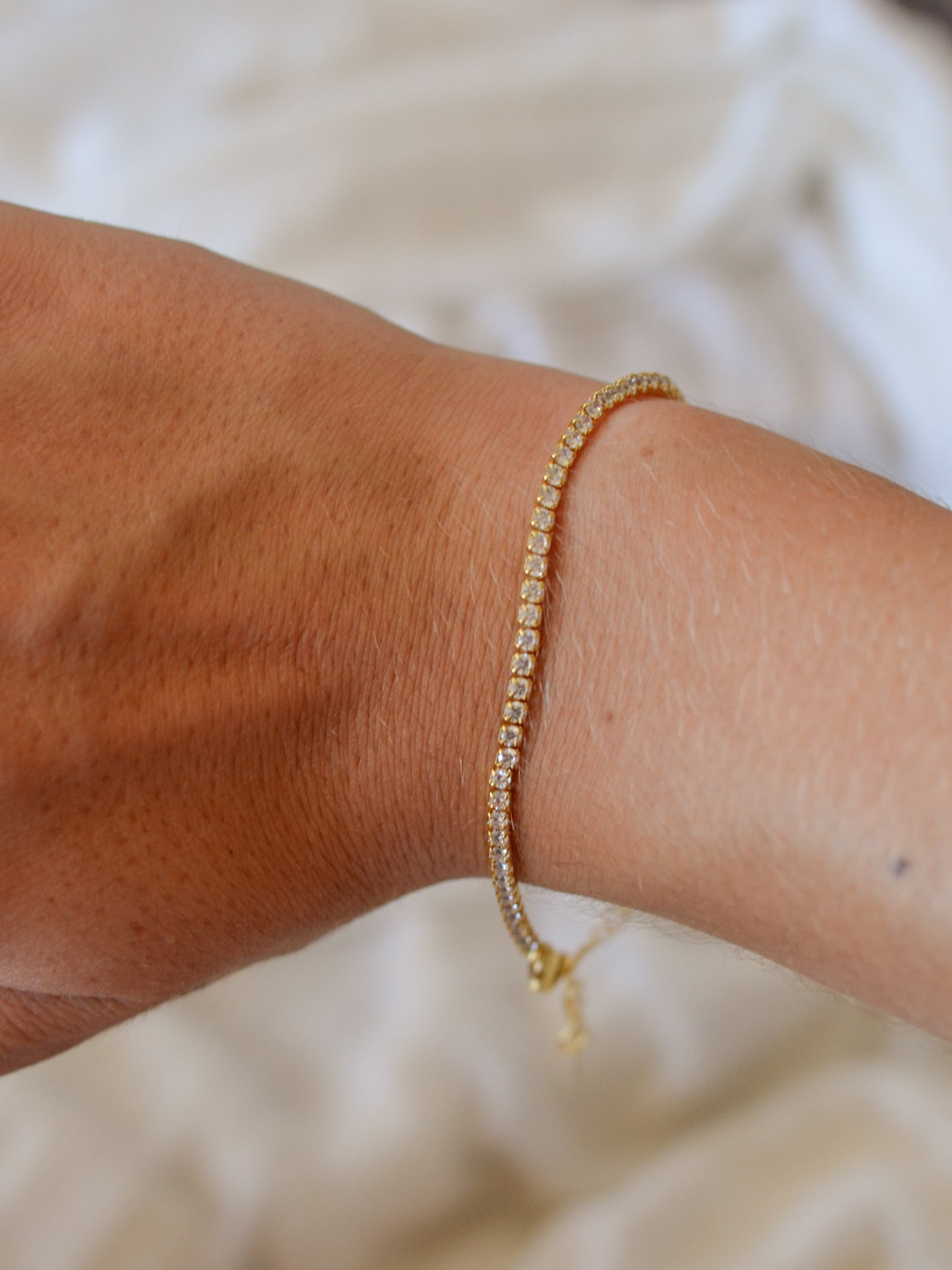 A gold chain tennis bracelet inlaid with cubic zirconia crystals.