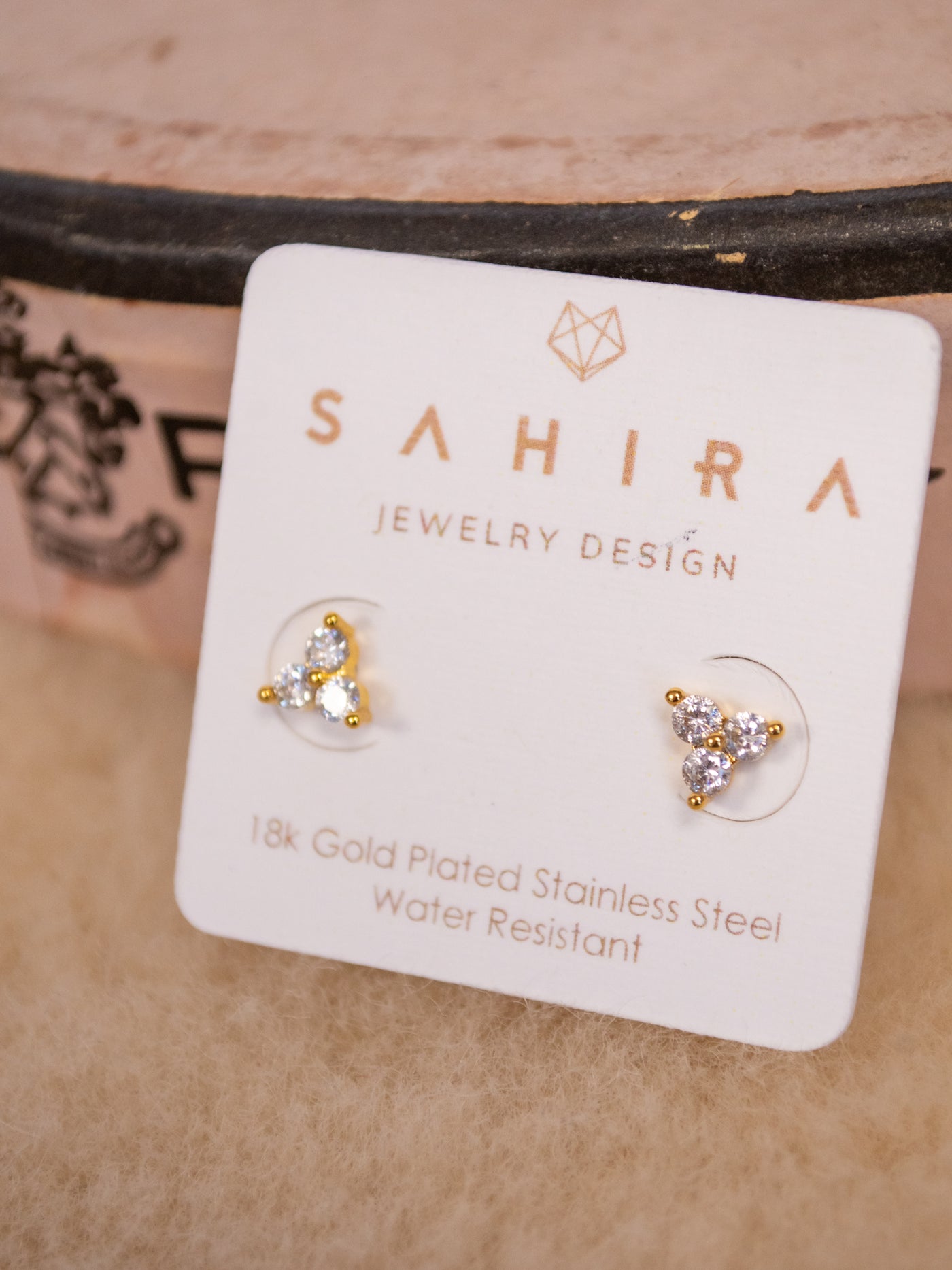 A pair of gold stud earrings with three CZ stones on them.