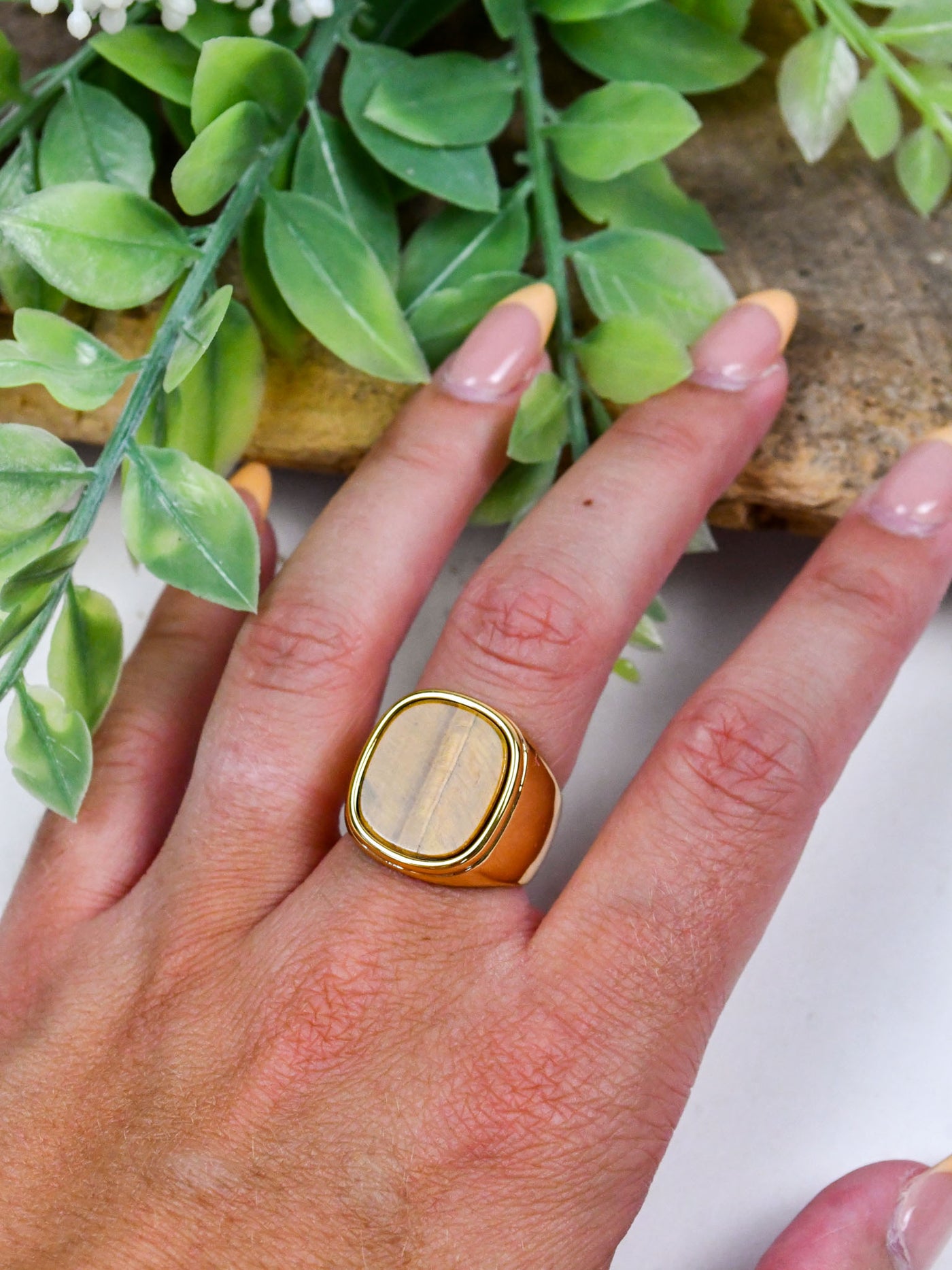 A gold ring with a brown wood-like stone center.