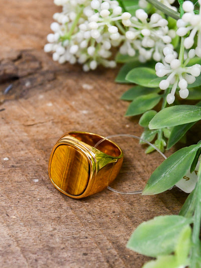 A gold ring with a brown wood-like stone center.