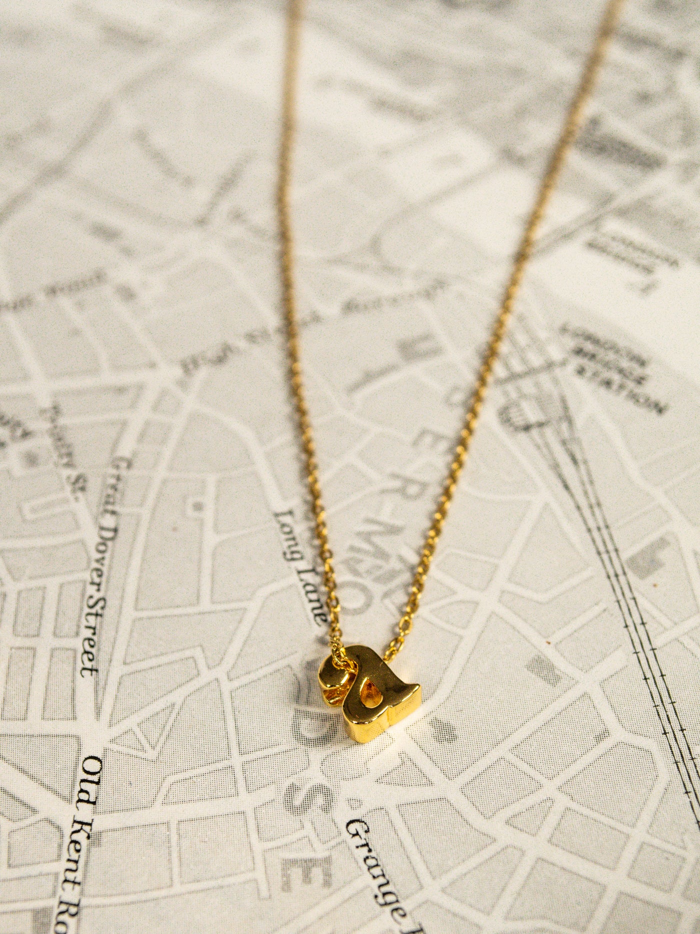 A gold mini, lowercase a initial necklace.