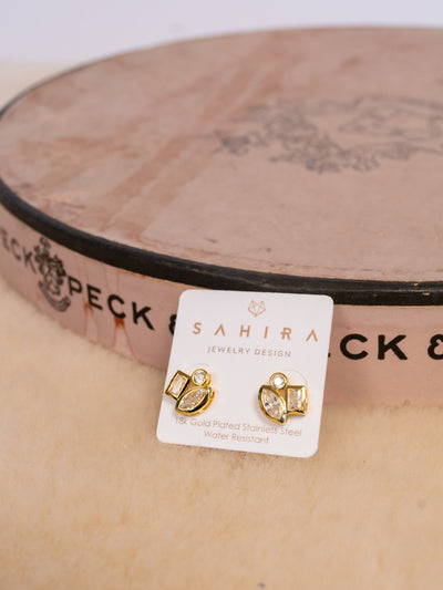A pair of gold studs with three CZ stones on the from. One is circular, one oval, and one rectangle.