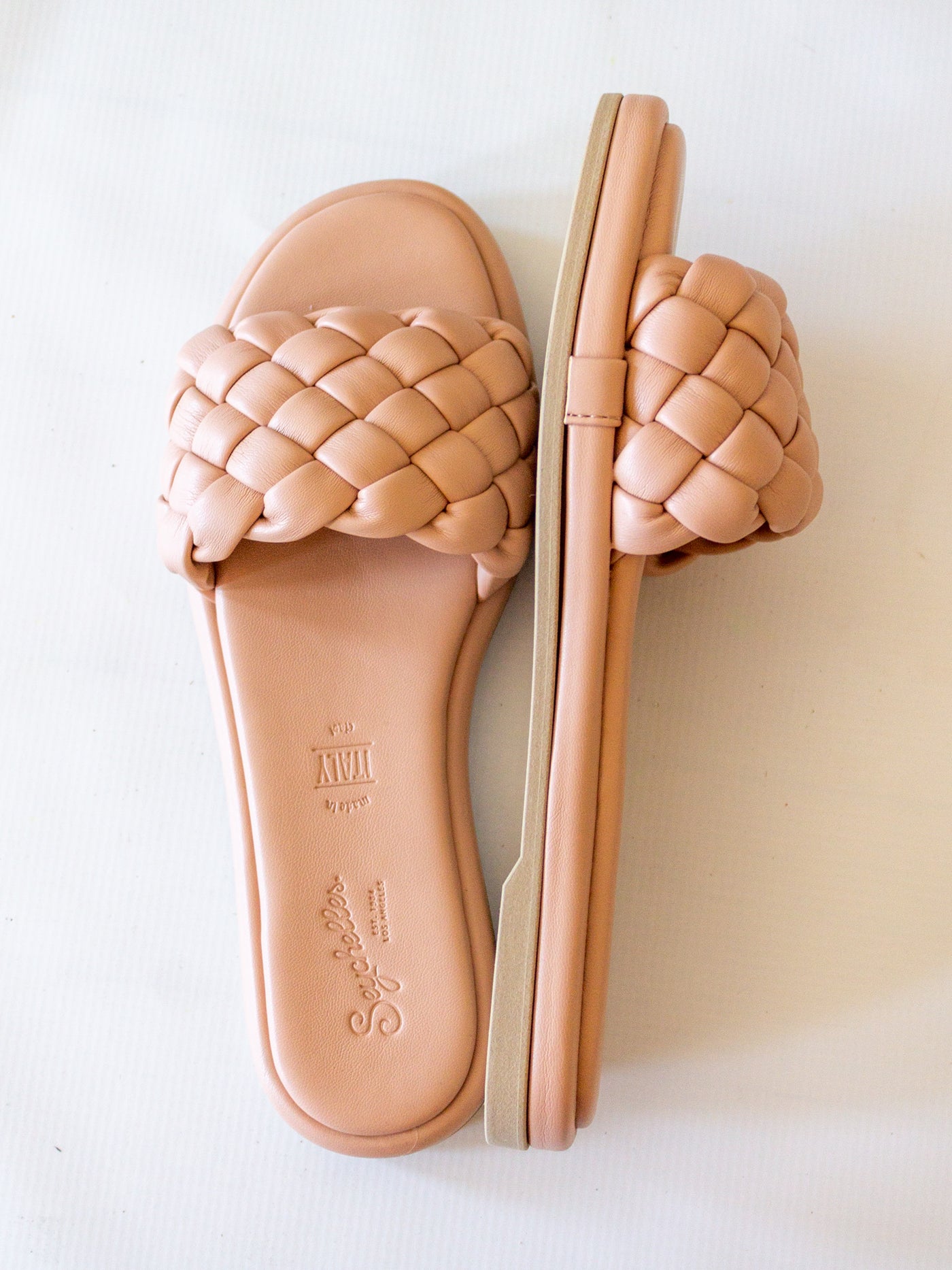 A pair a blush pink braided slide sandals.