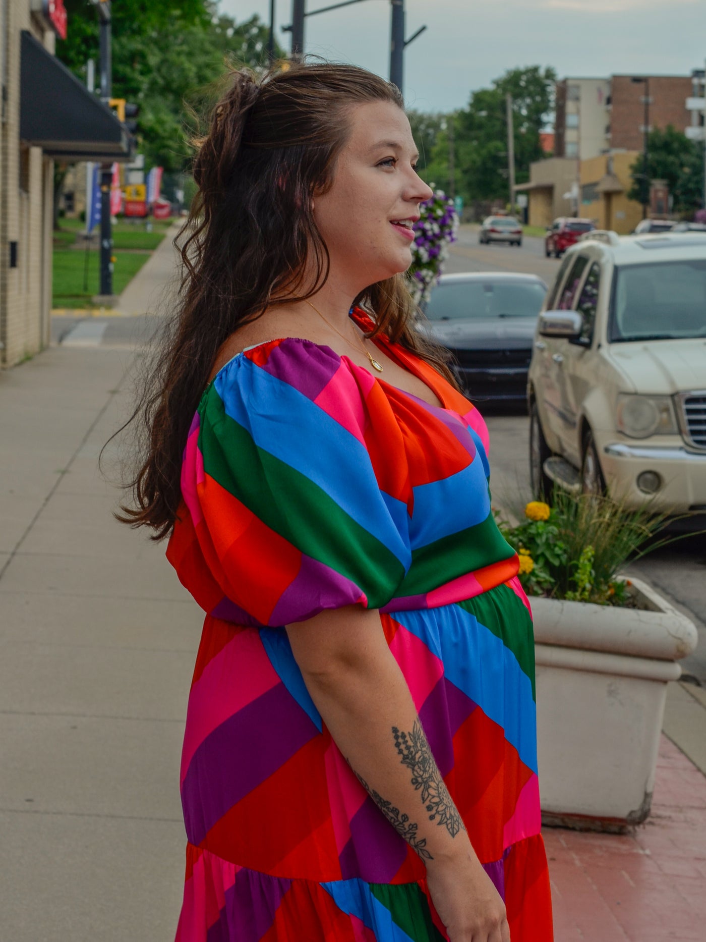 A model wearing a maxi dress with a v neck, puff sleeves, and a colorblock pattern.