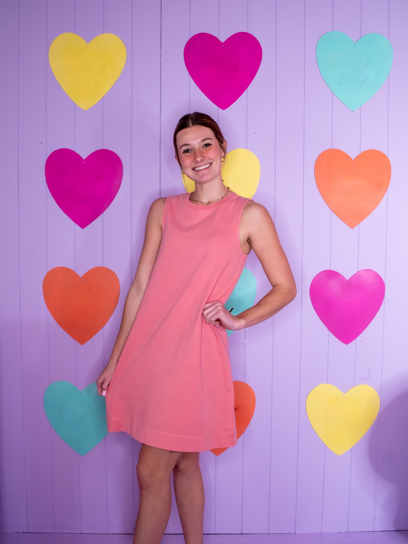 A model wearing a pink sleeveless dress with a crew neckline that hits right above the knee.