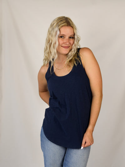 A model wearing a navy slub, relaxed fit tank top with a curved hem. Th model has it on with light wash denim jeans.